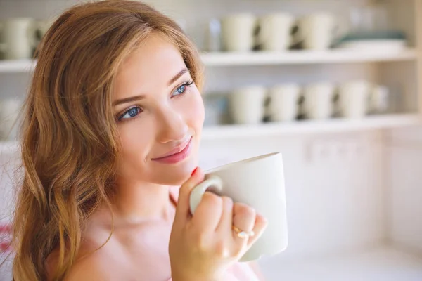 キッチンで素敵な女の子は マグカップから飲み物を飲みます 朝の早めの朝食 — ストック写真