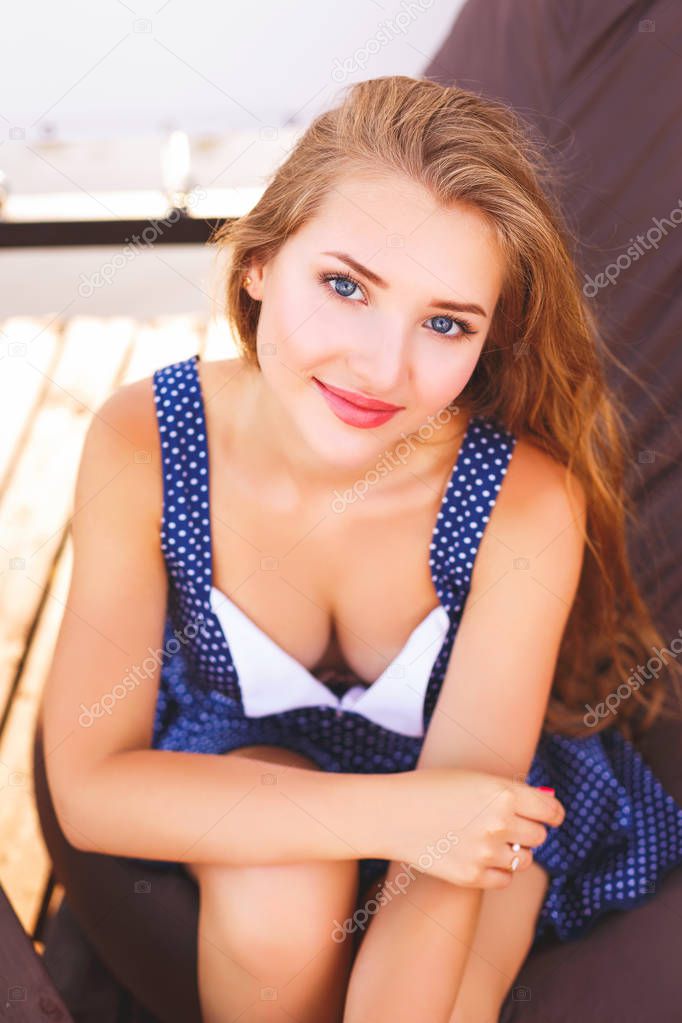 The girl is sitting on a soft armchair on a sunny day