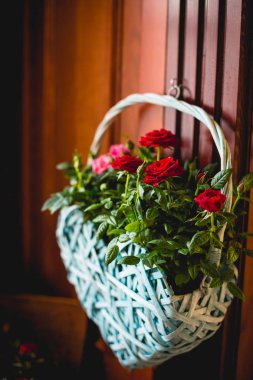 Kırmızı gül ahşap bir duvarda asılı olan büyük güzel beyaz sepet