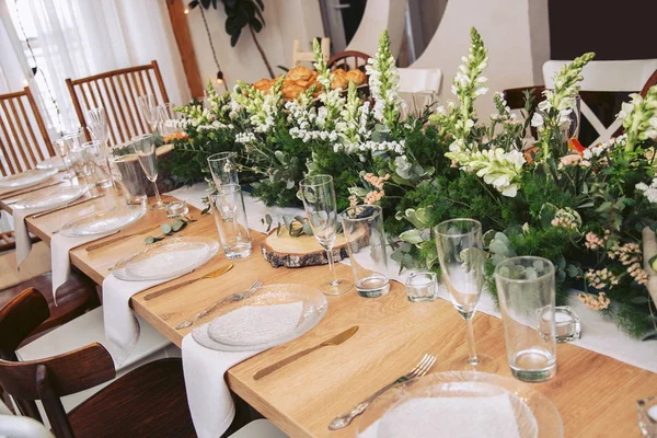 La table à l'intérieur du café est décorée avec des éléments en bois naturel et des bouquets de fleurs fraîches. Couverts sur la table . — Photo