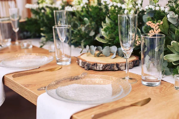 Mesa festiva con cubiertos. Mesa decorada con madera natural y verdes frescos . Imagen De Stock