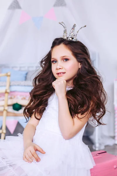 Niña con lujoso cabello oscuro posa con una corona en la cabeza. Celebraciones de cumpleaños de niños. La chica disfrazada de prncessy en el festival . — Foto de Stock