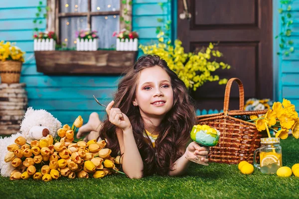 美妙的快乐女孩吃冰淇淋和微笑附近的黄色花。复活节庆祝活动在村里的房子的庭院野餐. — 图库照片