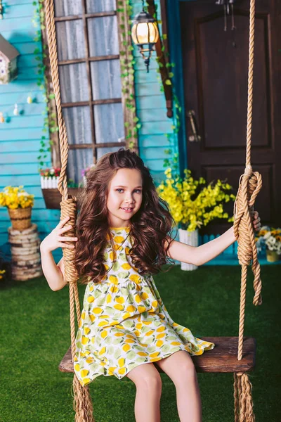 Menina cavalgando em um balanço no jardim perto da casa — Fotografia de Stock