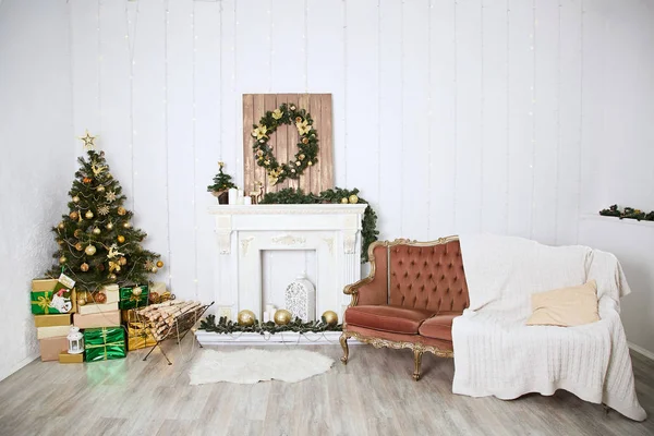 Intérieur dans un style classique dans une maison de campagne, décorée avec des éléments décoratifs pour Noël. Cheminée artificielle. Arbre de Noël vert avec cadeaux — Photo