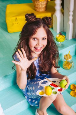 Neşeli sevimli kız boyalar ile boyanmış el gösterir. Paskalya kutlamaları için hazırlanıyor. Boyama Paskalya yumurtaları.