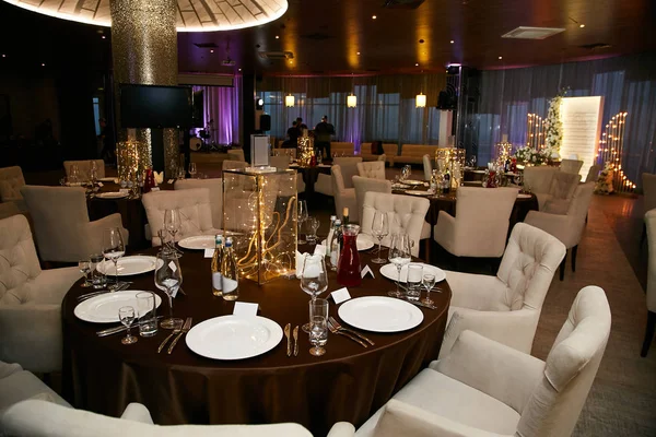 Банкетный зал в ресторане с мягкими белыми креслами. Праздник свадьбы. сервированный стол с декоративными элементами . — стоковое фото