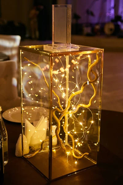 Cube décoratif en verre avec des fleurs et une guirlande aux lumières lumineuses . — Photo