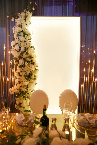 Стол молодоженов украшен гирляндой с красивыми лампами и букетом белых свежих цветов . — стоковое фото