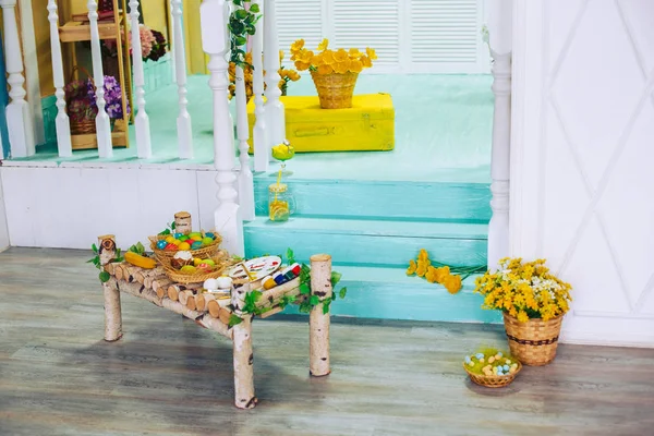 Interior de Pascua decorado con elementos naturales de madera y flores. Pinturas, coloridos huevos de Pascua en una canasta de mimbre . — Foto de Stock