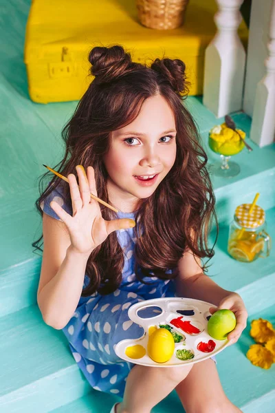 Uma menina com um belo penteado e cabelo escuro pintado ovos de Páscoa com cores. Preparando-se para as férias da Páscoa . — Fotografia de Stock