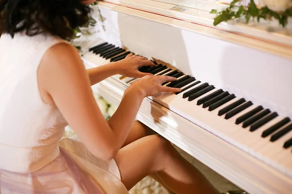 Meisje pianist speelt de witte piano tijdens een bruiloft viering. Stockafbeelding