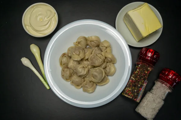 おいしい黒の背景に白いプレートにミンチ肉と自家製餃子を煮 若いタマネギの横に サワークリーム ナプキン — ストック写真