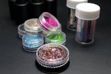 Siyah arka planda manikür ve pedikür için bir takım kozmetik aletler. Jel cilası ve dekoratif kabarcıklar.