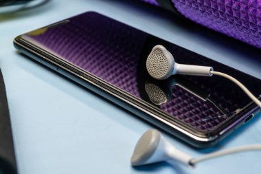 Mavi arka planda cep telefonu ve kulaklık.