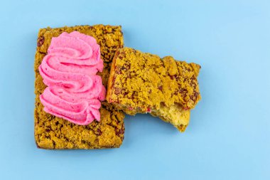 Üzerinde pembe şekerlemeler olan buğday ekmekli kurabiyeler ve üstünde pembe küçük çiçekler, mavi arka plan.