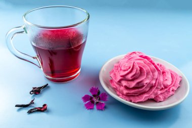 Mavi arka planda Hibiscus çay fincanı ve pembe marşmelov.