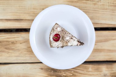 Beyaz bir tabakta üçgen bir Tiramisu keki. Ahşap arkaplan