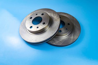 Otomobil parçaları, fren diskleri, pedler. Mavi arka planda iki fren diski.