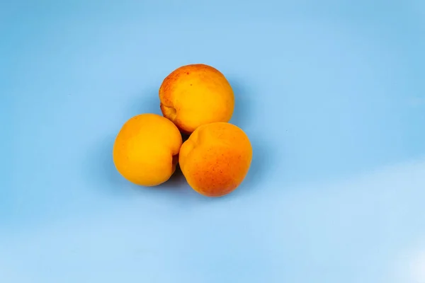 Trois Gros Abricots Mûrs Sur Fond Bleu — Photo