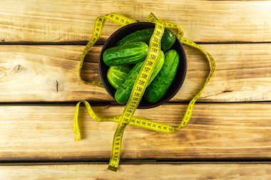 Kahverengi tabakta salatalıklar ve bir santimetre bant. Ahşap arkaplan