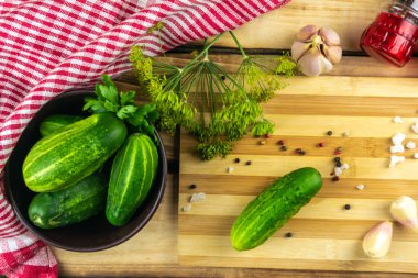 Kesme tahtasındaki yeşil salatalık, poşette salatalık, biber, tuz ve yeşilliklerin yanında. Ahşap arkaplan