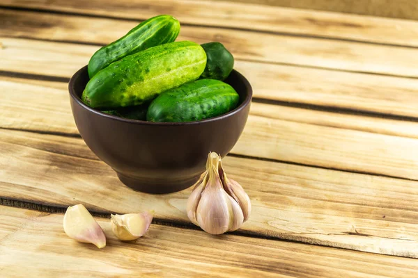 Pepinos Plato Marrón Cerca Del Ajo Fondo Madera —  Fotos de Stock