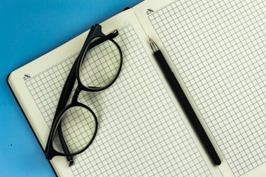 Gözlükler mavi arkaplanda bir deftere konur.