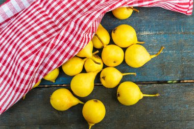 Kırmızı havluyla kaplı mavi bir zemin üzerine bir sürü sarı armut serpiştirildi.
