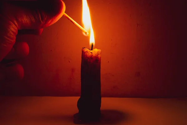 Candle in the twilight of a vintage night room with a match in hand
