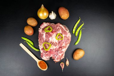 Çan biberiyle süslenmiş taze et diliminin en üst görüntüsü. Patates, soğan, sarımsak. Siyah arkaplan