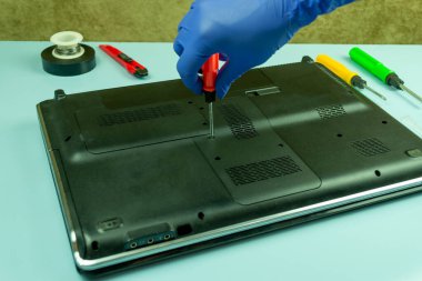 Bir tamirhanede dizüstü bilgisayar sökmek. Usta dizüstü bilgisayarı tornavidayla çeviriyor. Bilgisayar donanımı ve onarımı kavramı.