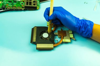 Bir tamirhanede dizüstü bilgisayar sökmek. Usta bir fırçayla bilgisayar parçalarının tozunu alıyor. Bilgisayar donanımı ve onarımı kavramı.