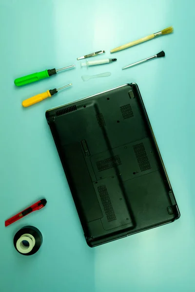 Disassembling a laptop in a repair shop. Laptop, screwdrivers, brushes. Concept for computer equipment, repair.