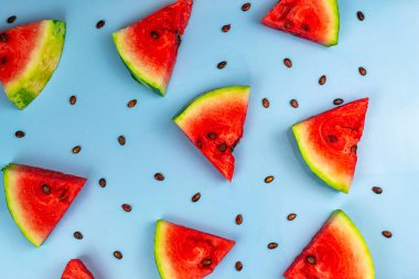 Mavi arka planda karpuz dilimleri ve karpuz tohumlarının üst görüntüsü