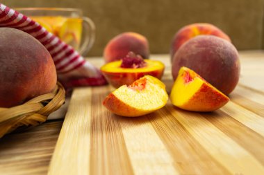 Hasır tabakta şeftali, kırmızı peçete, şeftali dilimleme tahtası ve yakın plan komposto. Ahşap arkaplan