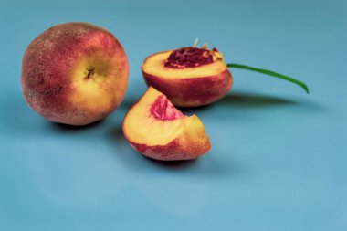 Büyük, sulu şeftali ve yarım. Mavi arkaplan yakın plan