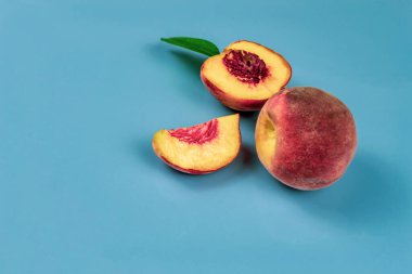 Büyük, sulu şeftali ve yarım. Mavi arkaplan yakın plan