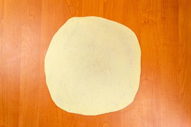 Pizza hamuru ince ince yuvarlanmış kırsal bir masada.