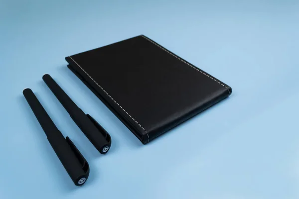 Μαύρο Σημειωματάριο Και Δύο Μαύρα Στυλό Ξαπλωμένα Δίπλα Του Ένα — Φωτογραφία Αρχείου