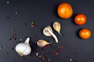 Olgun çiğ domates, siyah arka planda sarımsak..