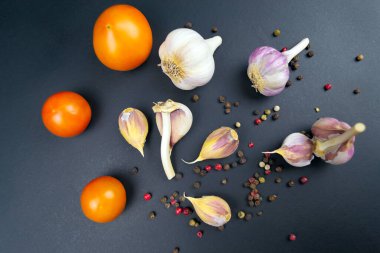 Olgun çiğ domates, siyah arka planda sarımsak..