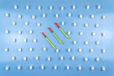 Şeker küpleriyle çevrili üç insülin şırıngası. Dünya Diyabet Günü