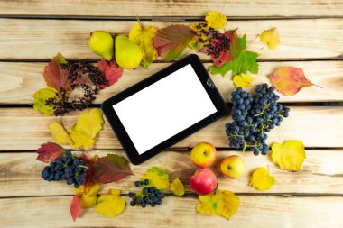Sonbahar meyve ve yapraklarıyla çevrili tabletin üst görüntüsü