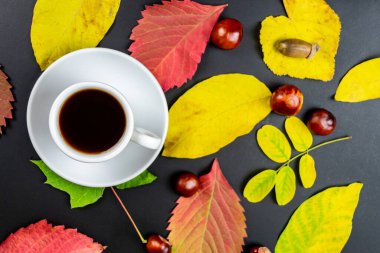 Siyah bir masada bir fincan kahve ve sonbahar yaprakları. Sonbahar konsepti