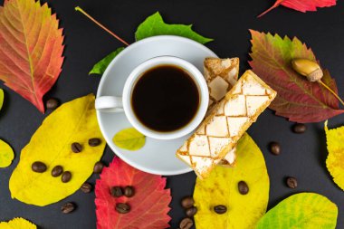 Siyah bir masada bir fincan kahve ve sonbahar yaprakları. Sonbahar konsepti