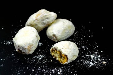 Siyah zemin üzerinde pudra şekerli beyaz kurabiyeler