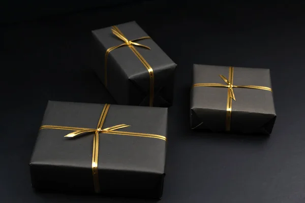 Gift boxes in black packaging on black background, black friday concept