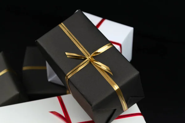 Gift boxes in black and white packaging on black background, black friday concept