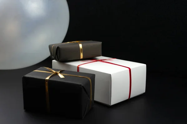 Gift boxes in black and white packaging on black background, black friday concept